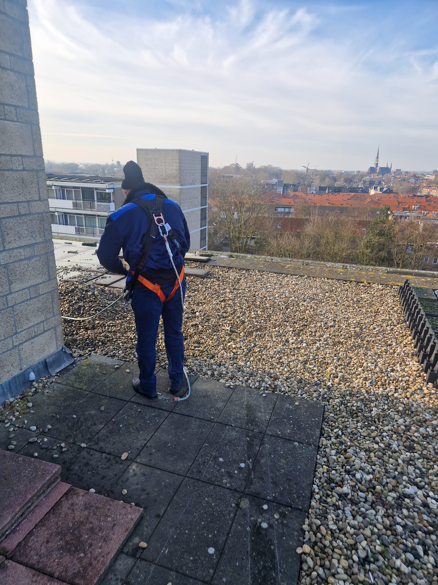 Lek Masters Amsterdam specialist op grindtap dak met veiligheidsharnas